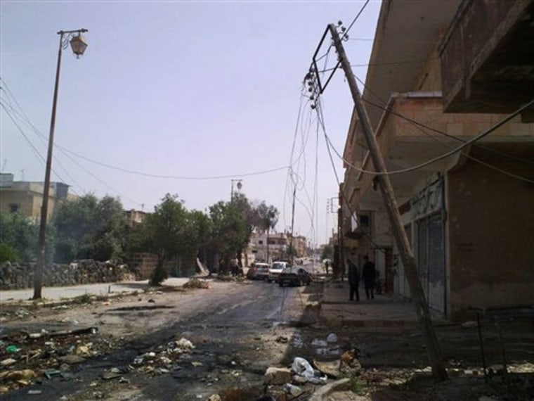 In this undated citizen journalism image made on a mobile phone and acquired by the AP, people walk in a damaged street in the southern city of Daraa, Syria. The Syrian army shelled residential areas and unleashed security forces on Wednesday.